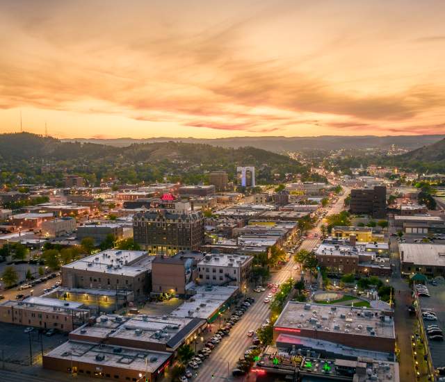 Drone shot overlooking downtown Rapid City with sunset in the background