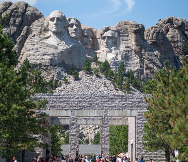 People walking through the memorial with Mount Rushmore in the background