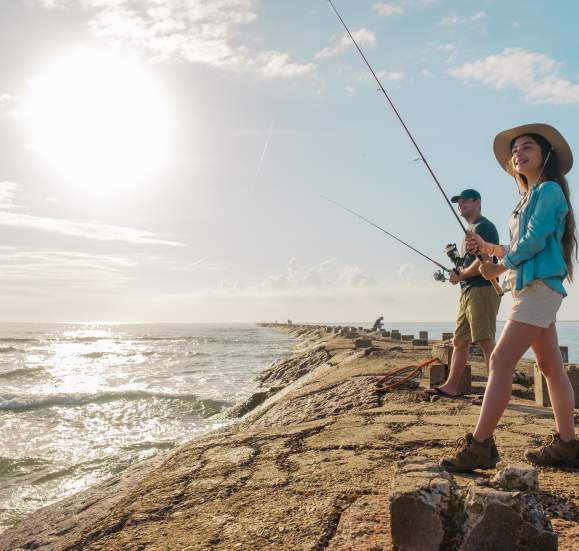 Father and daughter fishing off the jetties on a sunny bright day