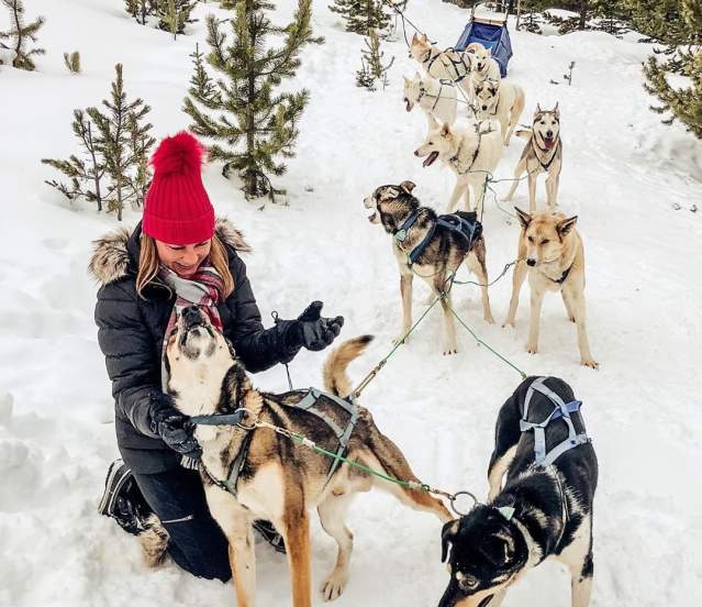Photo by user hauteholidaystravel, caption reads Dog (sledding) days of winter 🐾❄️🤗 #hauteholidaystravel #dogsledding #bigsky #moonlightbasin #montanamoment