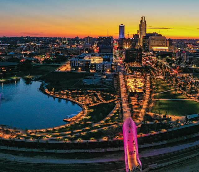 A vibrant sunset skyline shot of Omaha, Nebraska showing pink lights from Heartland of America Park and Farnam Pier.