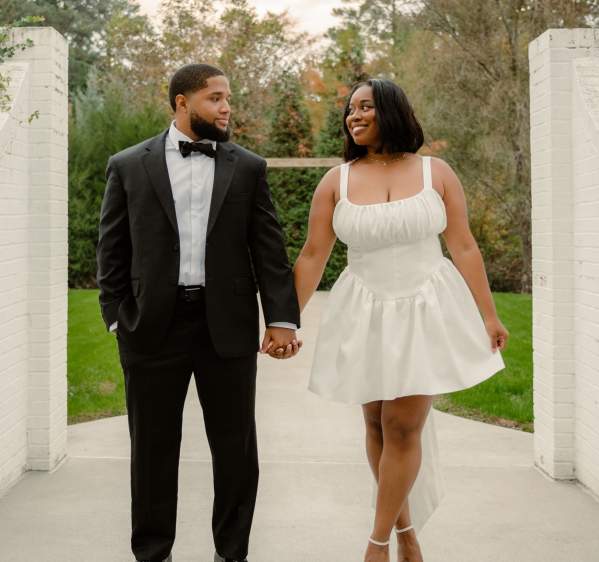 Bride and groom walking hand in hand through a garden archway at Vizcaya Villa in Cumberland County