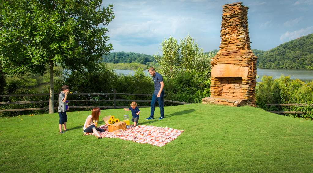 A family setting up for a picnic on the grass at Morgan Falls Overlook Park in Sandy Springs, Georgia over by the fireplace.