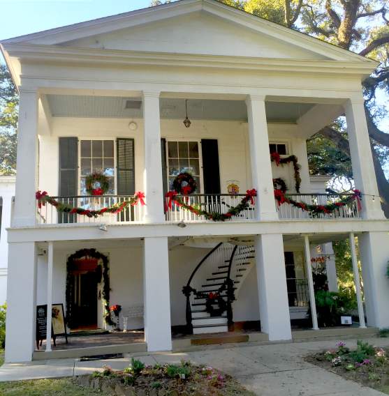 white two-story building with four columns and Christmas wreaths and garland