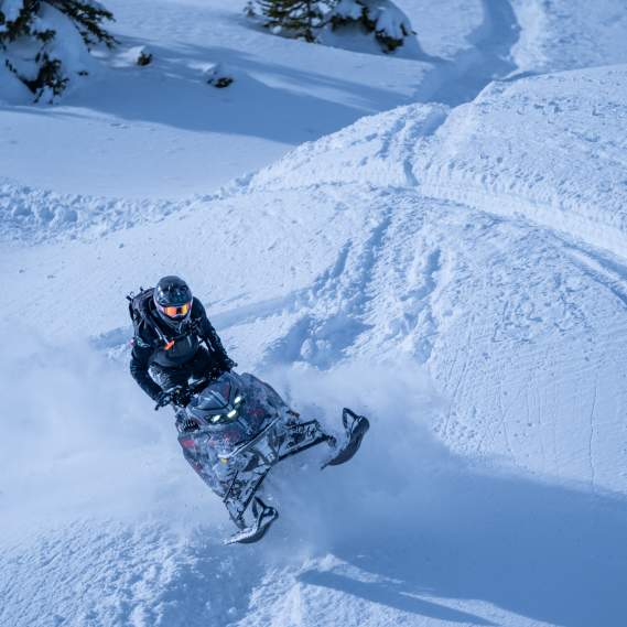 Snowmobile going over a hill in deep snow