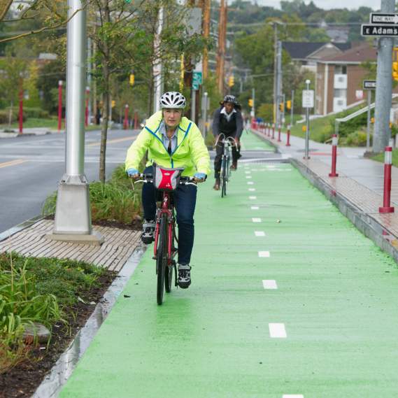 Man Rides Bike with Helmet in Green Bike Lanes Through Syracuse
