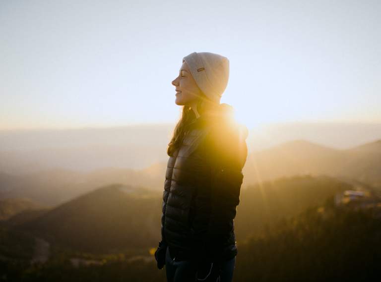 Woman on top of mountain in front of the sunrise
