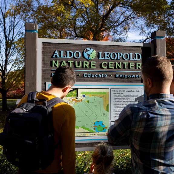 Two dads and their daughters reading a sign at the Aldo Leopold Nature Center