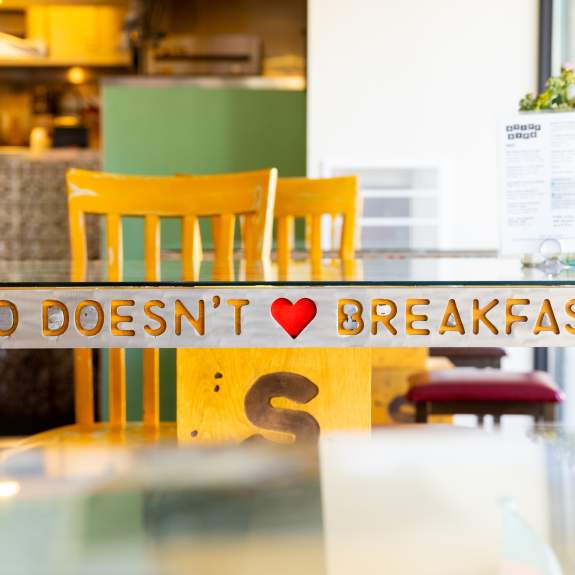 An image of a table at Short Stack Eatery with the words "Who doesn't love breakfast" engraved into the side