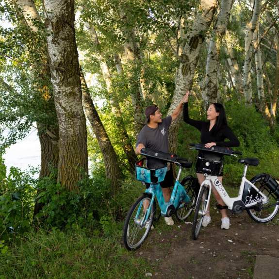 Two cyclists high five each other in front of Lake Monona and Olin Park