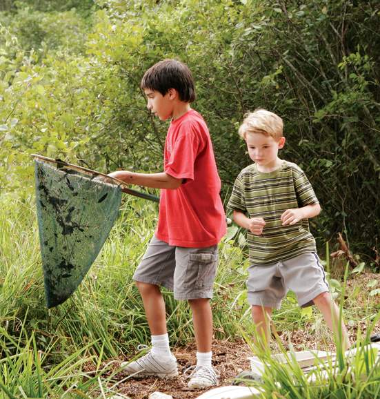 Two boys, one holding a net, on a walking trail surrounded by greenery in Sandy Springs, GA