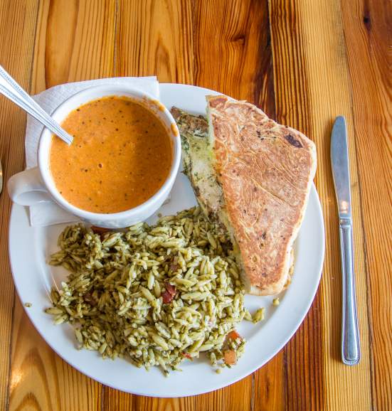 Soup, rice and a sandwich on a wood table.