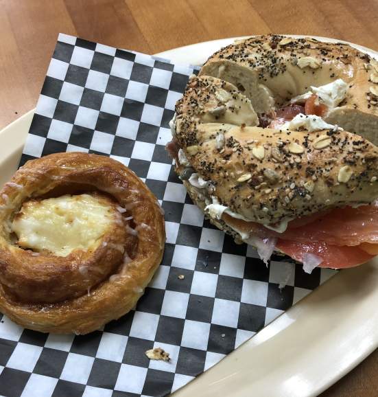 A Danish and bagel sitting on checkered paper on a plate at City Bagel Cafe in Sandy Springs.