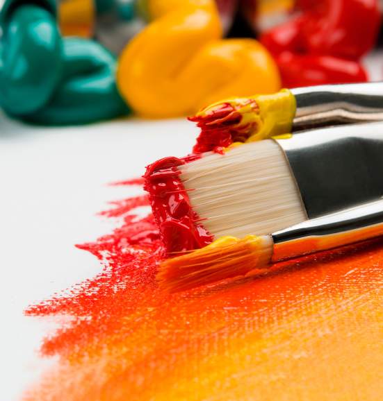 Paint brushes with red and orange paint on a white canvas.