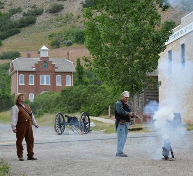 Two men in 1800s dress demonstrating cannon and gunfire