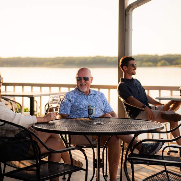 Three people enjoying drinks on the patio at the Point Restaurant which overlooks Lake Texoma