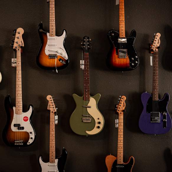 A variety of electric guitars are hanging on a dark gray wall.