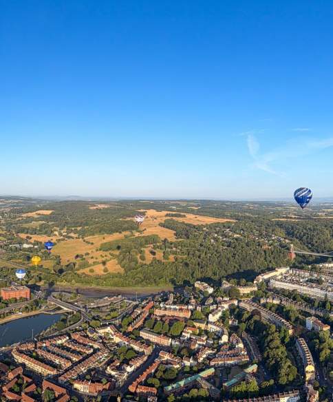 A panoramic ariel view over Bristol with multiple hot air balloons