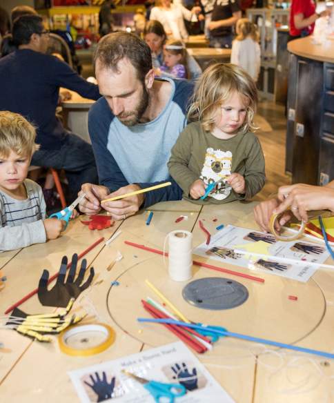 Family trying the bionic hands activity at We The Curious Bristol - credit Paul Blakemore