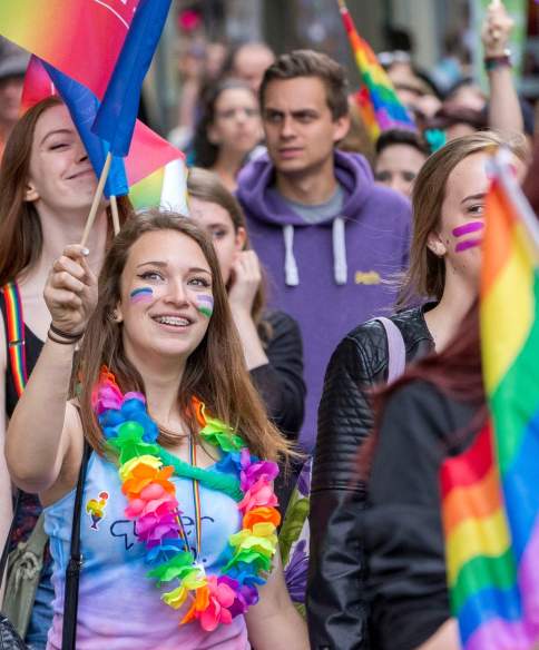 People walking in the Bristol Pride parade wearing rainbow accessories - Credit Paul Box