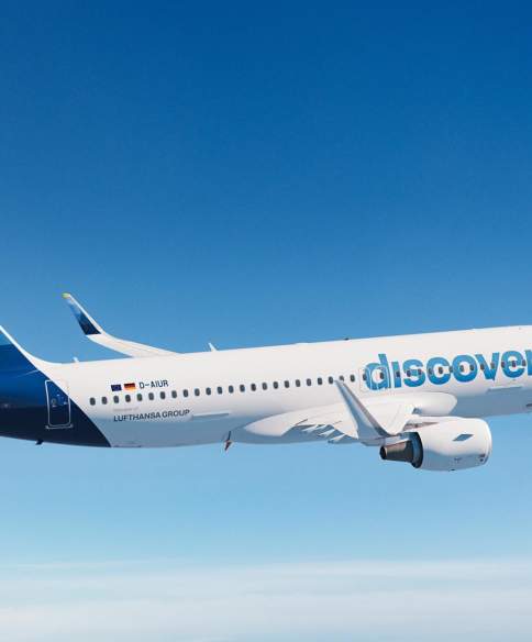 An image of a Discover Airlines plane flying through the sky.
