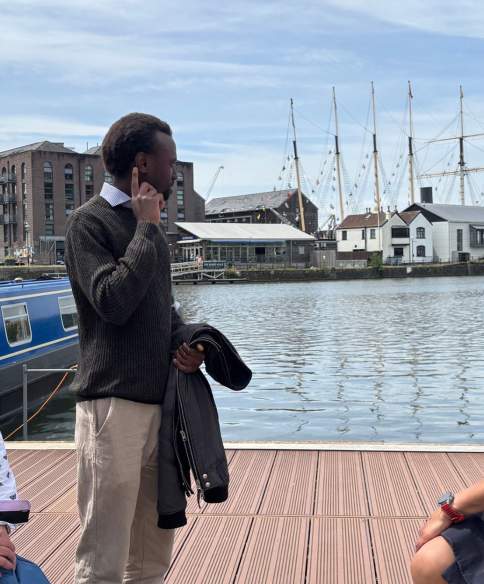 3 people sat on decking next to Bristol Harbour