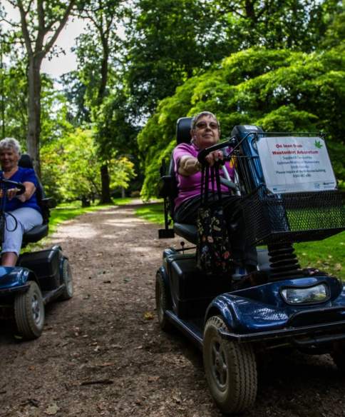 Two mobility scooter users on a path at Westonbirt Arboretum - credit Johnny Hathaway