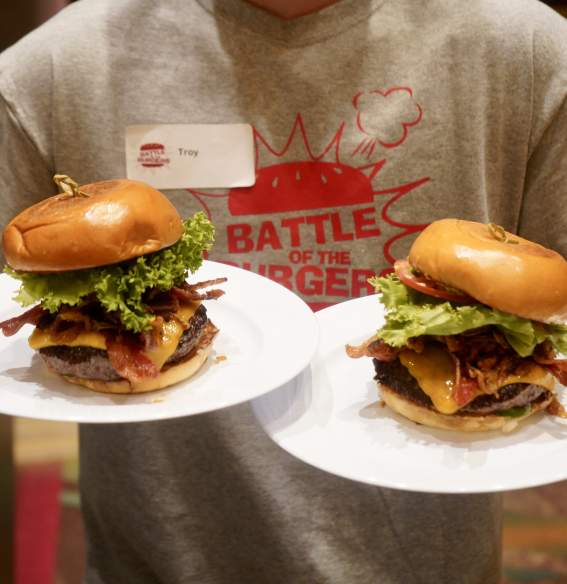 A person holding two burgers on plates