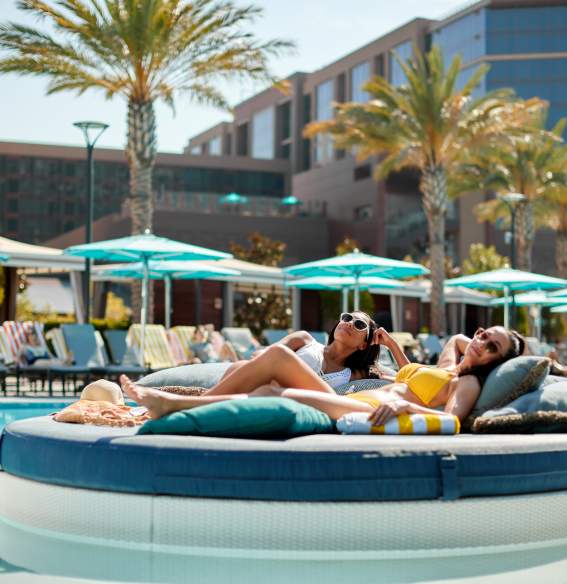 Two women relaxing on a bed, poolside