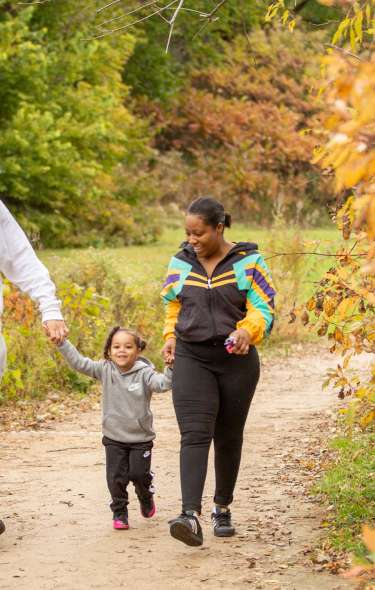 A family takes a walk down a trail surrounded by fall colors