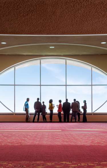 Folks inside of the Monona Terrace Convention Center looking out the window at Lake Monona.