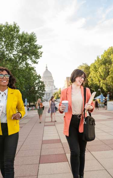 People walking towards the Monona Terrace with the Capitol Building in the background
