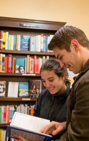 Two people browse a selection of books inside A Room of One's Own bookstore