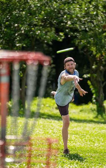 A man takes aim at a disc golf basket at Elver Park