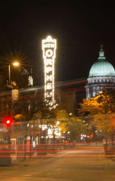 A view of a lit up State Capitol and Orpheum sign at night from State Street