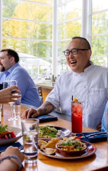 Chef Tory Miller talks to a table of people while they eat their meal at Graze