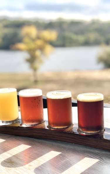 A flight of beer sits on a table outdoors