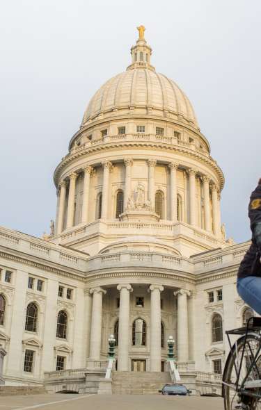 A woman rides her bike in front of the State capitol