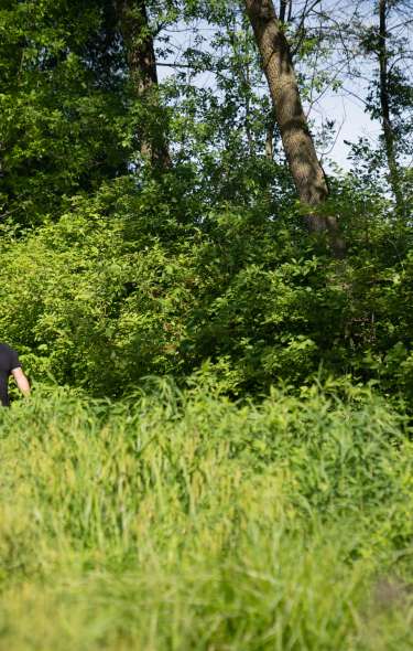 A man and woman hike along a wooded area