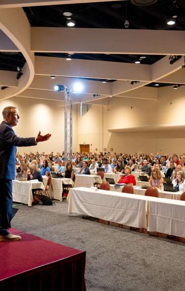 Speaker gesturing toward audience at a teacher conference at Monona Terrace Community & Convention Center
