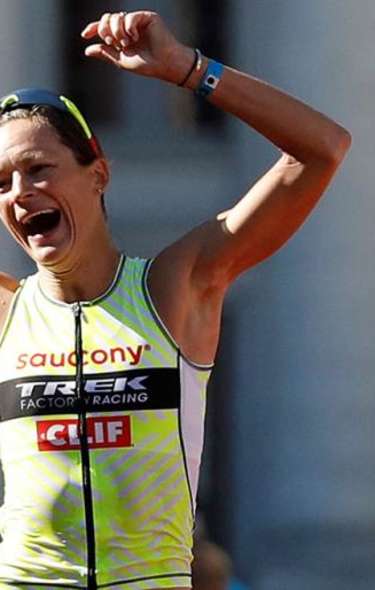 A white woman runner celebrates finishing a race in Downtown Madison in front of the Capitol building. People in the crowd reach out to give her a high five