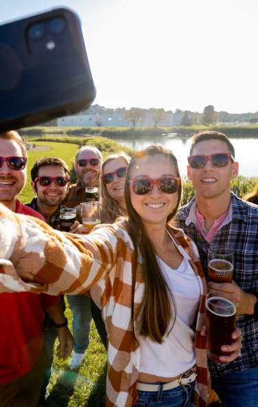 A group of friends take a selfie on a sunny day with beers in their hands at Wisconsin Brewing Company