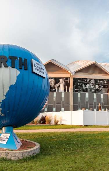 An image of the outside of Alliant Energy Center during the CrossFit Games. The CrossFit Games globe statue is in front of the Alliant Energy Center.