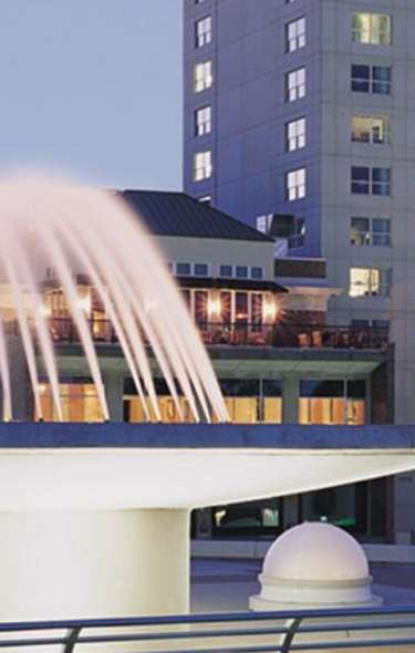 A close up view of the fountain spewing water at the Hilton Madison Monona Terrace. The Capitol building and other downtown buildings are in the background