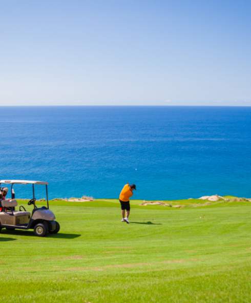 fotografía de personas jugando en un campo de golf con vista al mar