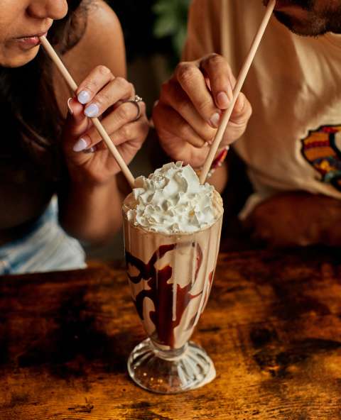 Two people using straws to drink a milkshake.
