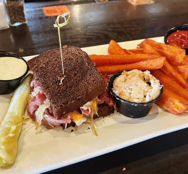 A Reuben sandwich on dark rye is served at Murphy’s with sweet potato fries, a pickle spear, potato salad and dipping sauces.