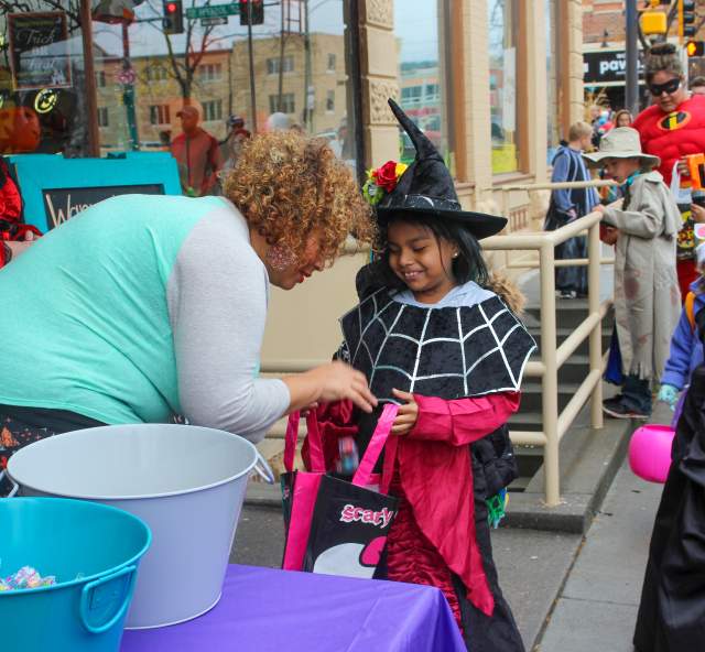 Child dressed in a witch costume collecting candy from a downtown business owner as part of the Downtown Trick-or-Treat event in Rapid City, SD.