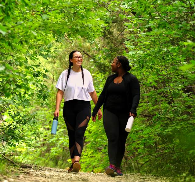 Young female friends walking on green trail