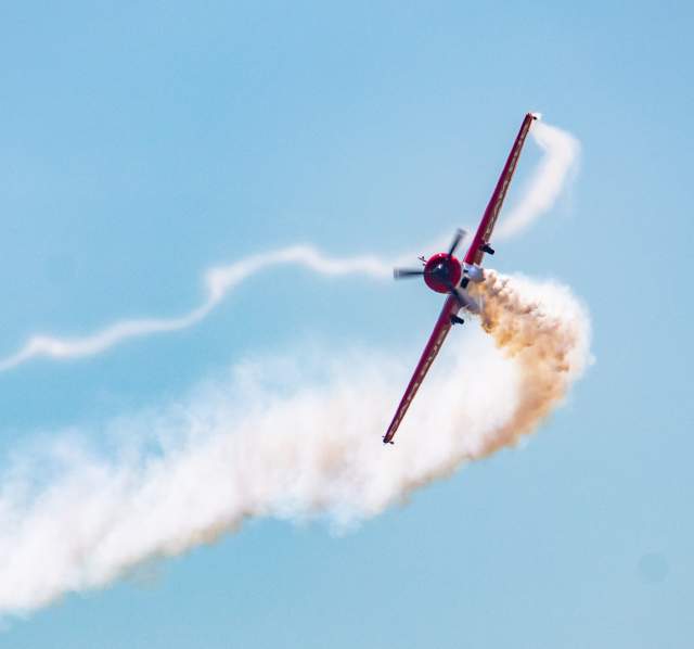 plane flying at airshow with trail of smoke